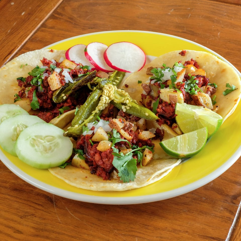 Three Plaza Garibaldi Mezcaleria tacos with chorizo, potatoes, cilantro, onions, peppers, radishes, cucumbers, and lime.